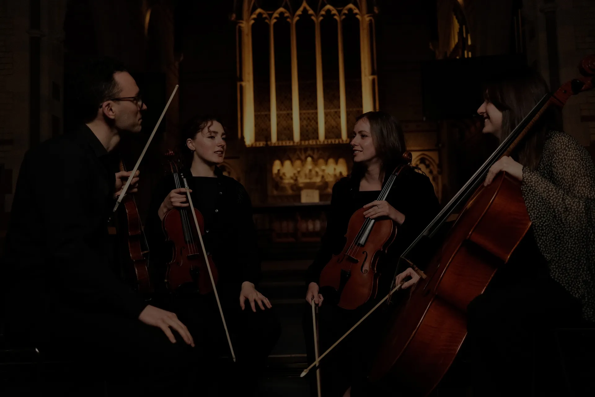 The four members of Seas Quartet with their instruments in a candlelit church